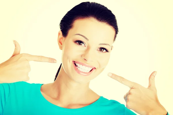 Schöne Frau zeigt auf ihre weißen Zähne. — Stockfoto