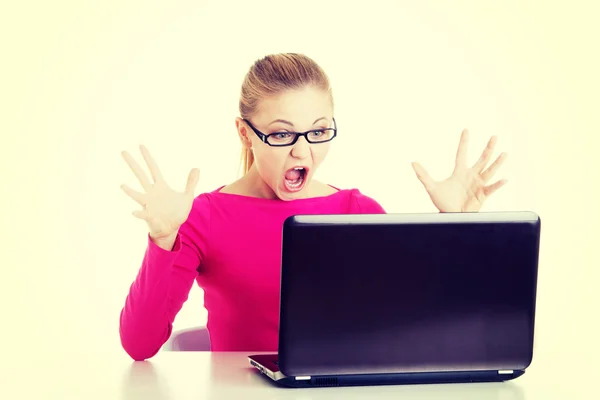 Jonge vrouw achter laptop zit verrast. — Stockfoto