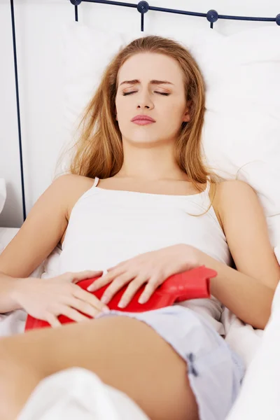 Närbild på kvinna med varmvattenflaska i sängen — Stockfoto