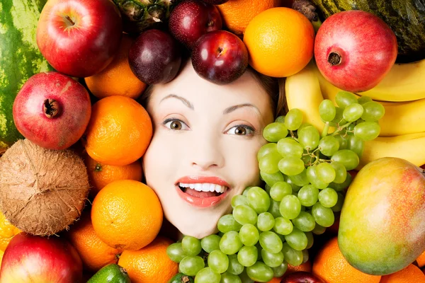 Young woman in group of fruit. — Stock Photo, Image