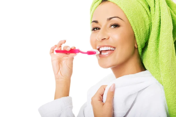 Woman in bathrobe brushing teeth — Stock Photo, Image