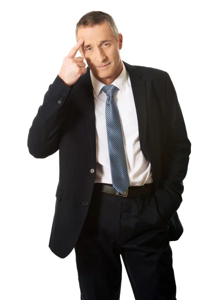 Businessman gesturing with finger against temple — Stock Photo, Image