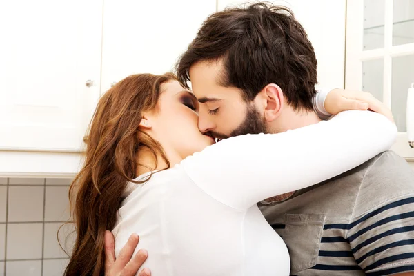 Happy beautiful couple kissing in the kitchen. — Stock Photo, Image