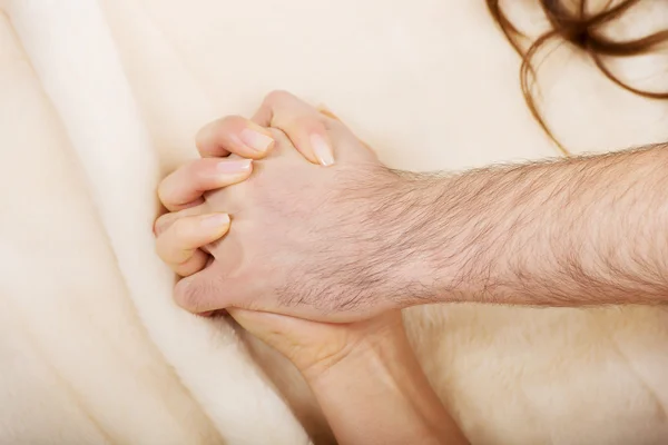 Mãos de casal deitado na cama — Fotografia de Stock