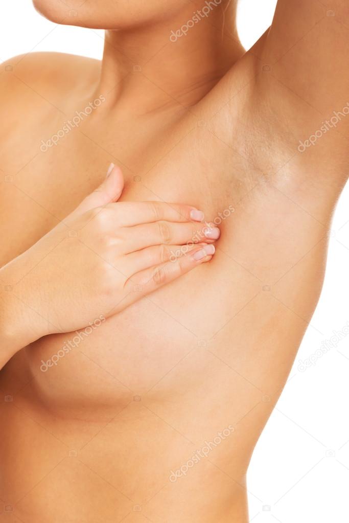 Nude woman examining her breast