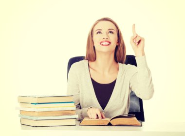 Kitap yığını tarafından oturan ve yukarı dönük kadın.