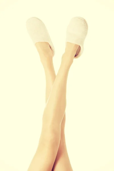 Женские ноги с белыми тапочками . — стоковое фото