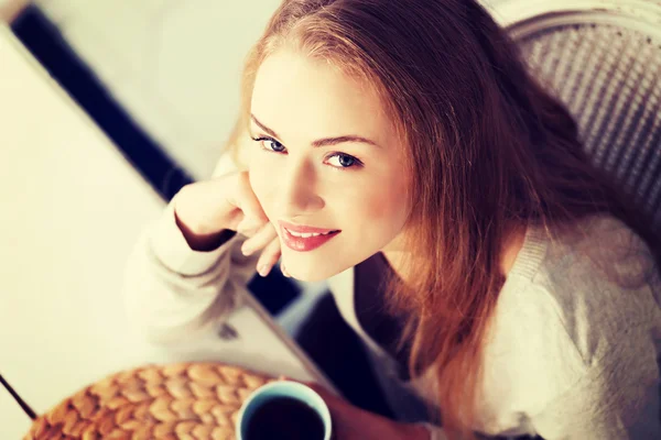 Vacker kaukasisk kvinna sitter vid ett bord. — Stockfoto