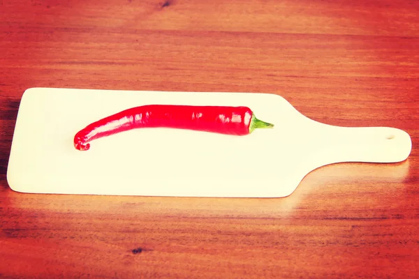 Fresh chili pepper lying on kitchen board. — Stock Photo, Image