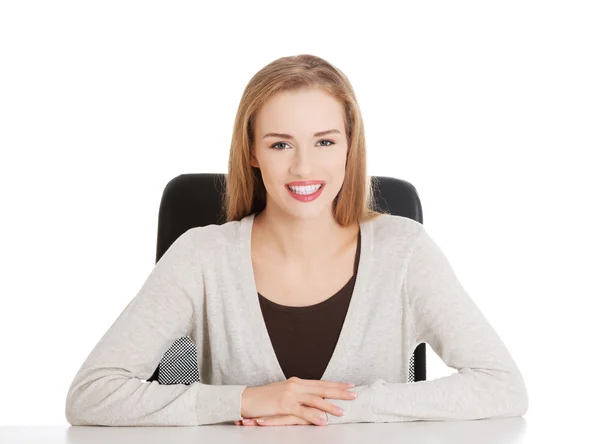 Χαμογελαστή γυναίκα που κάθεται από ένα γραφείο. — Φωτογραφία Αρχείου