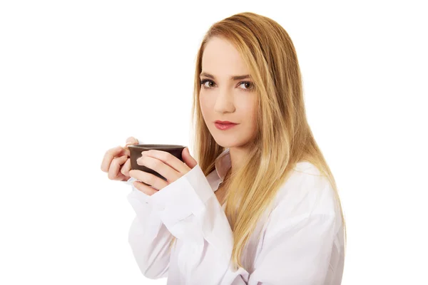 Женщина в рубашке с длинным рукавом пьет кофе . — стоковое фото