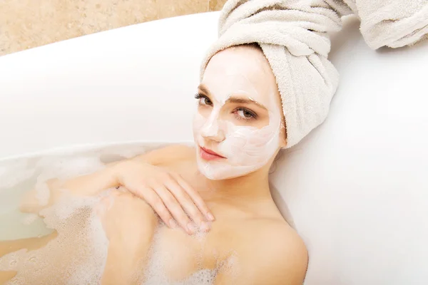 Woman relaxing in bathtub with face mask. — Stock Photo, Image