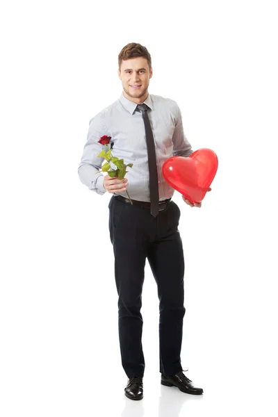 Mladý muž s červenou růži a balónek srdce. — Stock fotografie