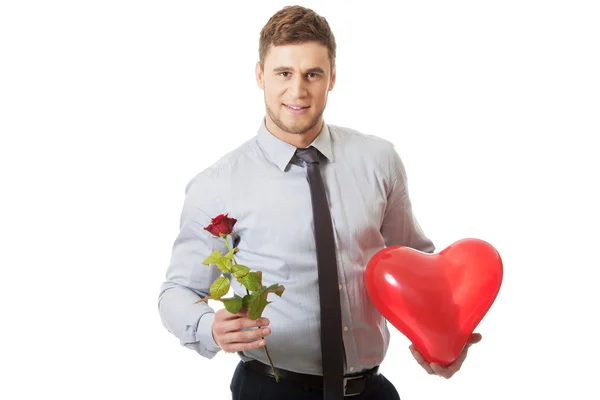 Mladý muž s červenou růži a balónek srdce. — Stock fotografie