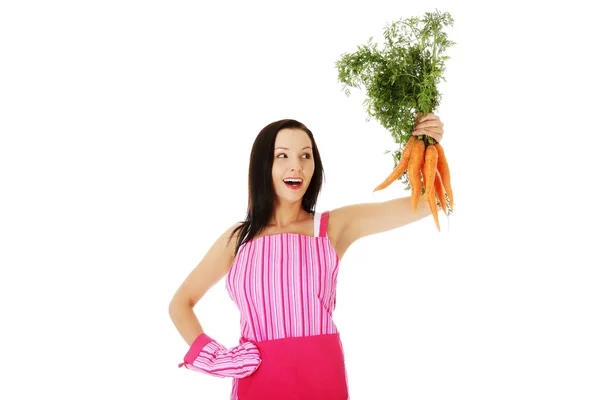 Привлекательная домохозяйка держит кучу моркови — стоковое фото