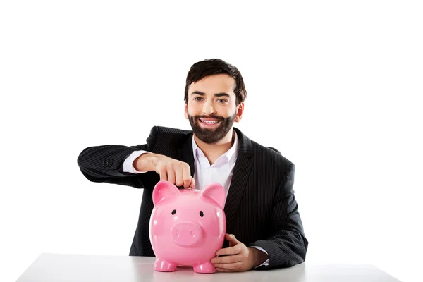 Affärsman att sätta ett mynt för piggybank. — Stockfoto