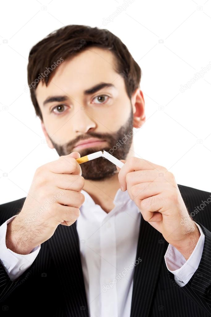 Businessman breaking a cigarette.