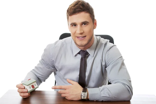 Geschäftsmann mit Hausmodell am Schreibtisch. — Stockfoto