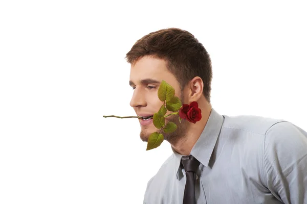 Schöner Mann mit roter Rose im Mund. — Stockfoto