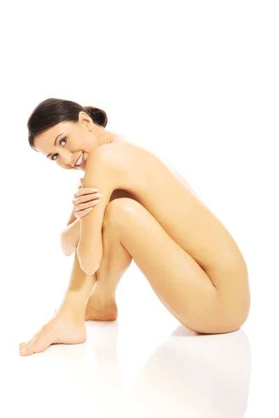 Seitenansicht einer nackten Frau, die sitzt und sich umarmt — Stockfoto