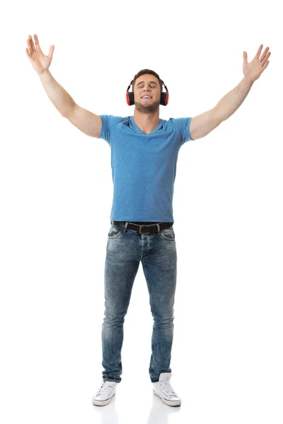 英俊潇洒的男人用耳机听音乐. — 图库照片