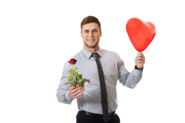 Jonge man met een rode roos en hart ballon. Stockfoto