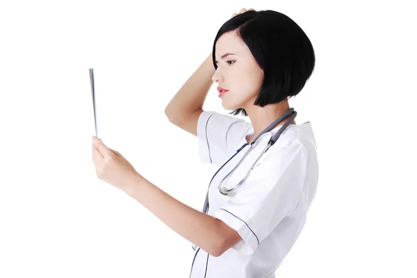 Worried female doctor analysing x-ray image — Stock Photo, Image