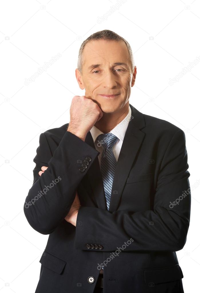 Happy mature businessman with hand under chin