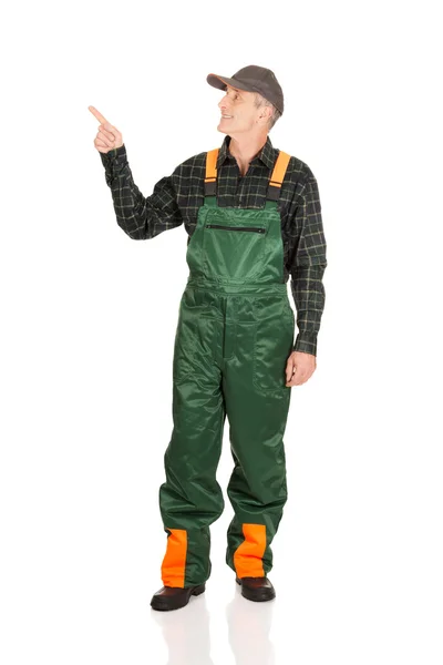 Mature gardener in uniform pointing up — Stock Photo, Image