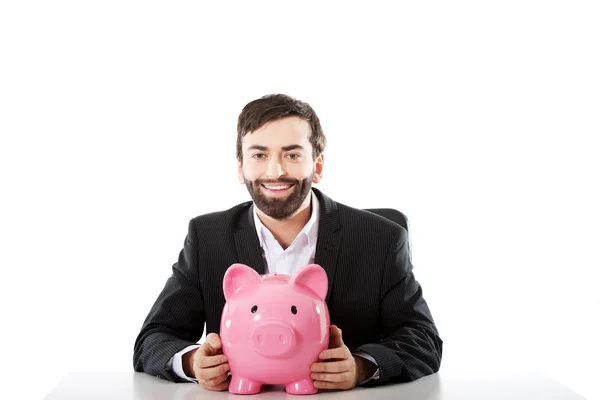 Businessman with piggybank by a desk. — Stock Photo, Image
