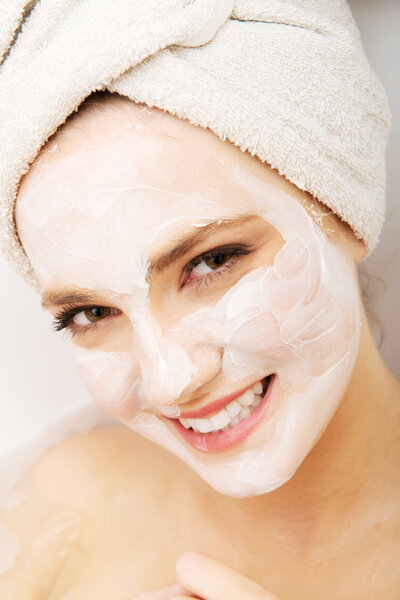 Woman relaxing in bathtub with face mask.