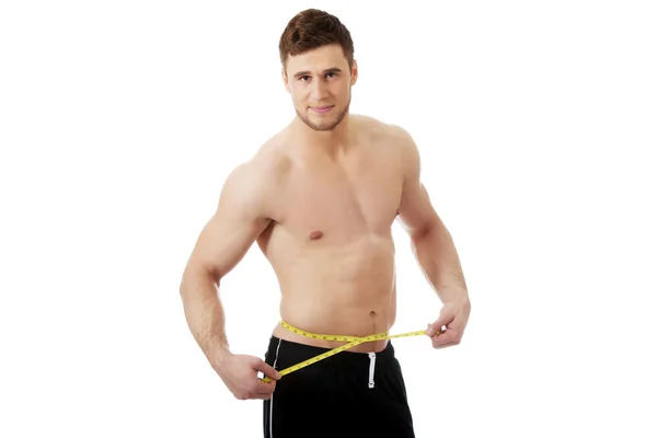 Muscular man measuring his belly. — Stock Photo, Image