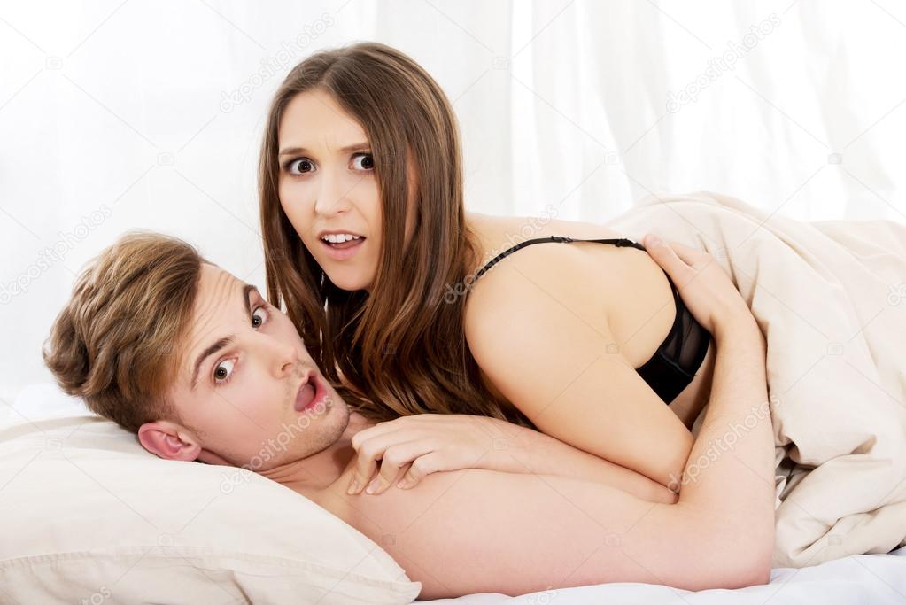 Shocked couple lying on bed.