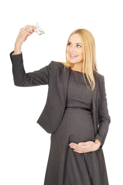 Pregnant businesswoman holding plane model — Stock Photo, Image