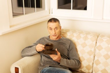 Kahve içip kanepede oturan adam