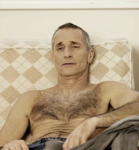 Shirtless man zit op een sofa — Stockfoto