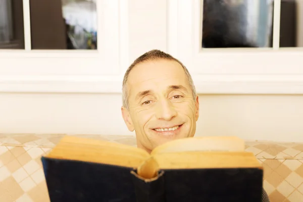 Ontspannen volwassen man lezen van een boek in woonkamer — ストック写真