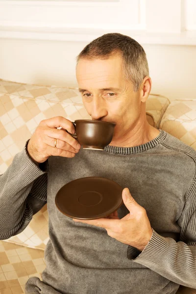 Mann sitzt auf Couch und trinkt Kaffee — Stockfoto