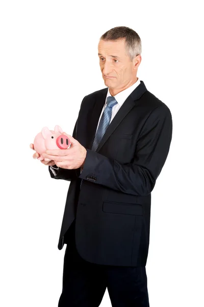 Homem de negócios confuso segurando piggybank — Fotografia de Stock