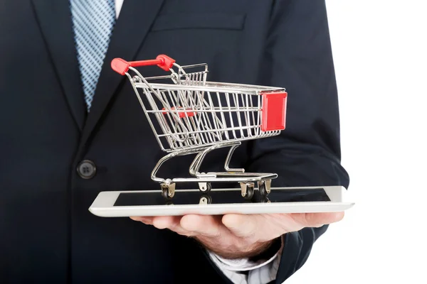 Empresario sosteniendo carrito de compras en la tableta — Foto de Stock