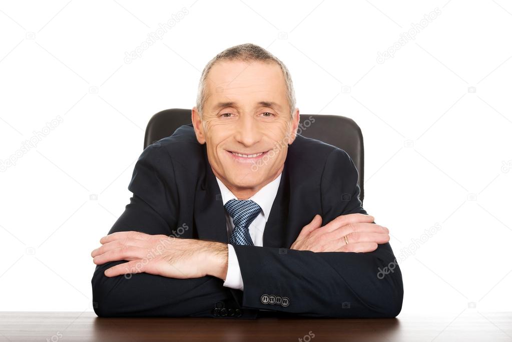 Happy businessman sitting at his desk