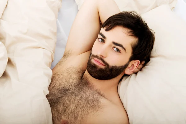 Uomo muscolare sdraiato a letto . — Foto Stock