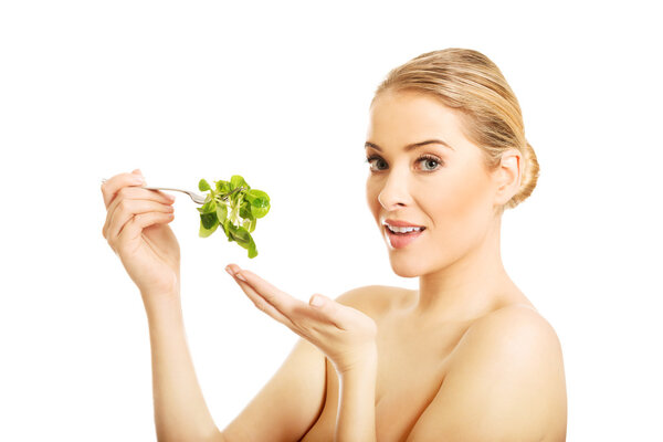 Nude woman eating lettuce