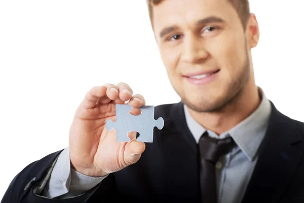 Бизнесмен держит кусочек головоломки . — стоковое фото