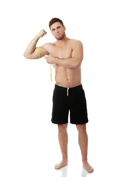 Hombre musculoso midiendo sus bíceps . — Foto de Stock