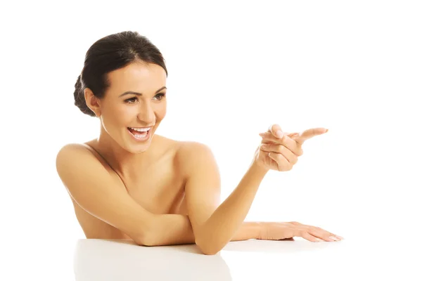 Spa woman sitting at desk pointing to the right — Stock Photo, Image