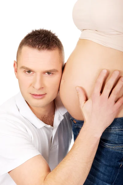 Pai ouvindo a barriga grávida da mãe — Fotografia de Stock