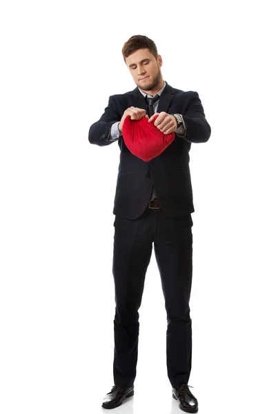 Businessman tears heart shaped pillow. — Stock Photo, Image