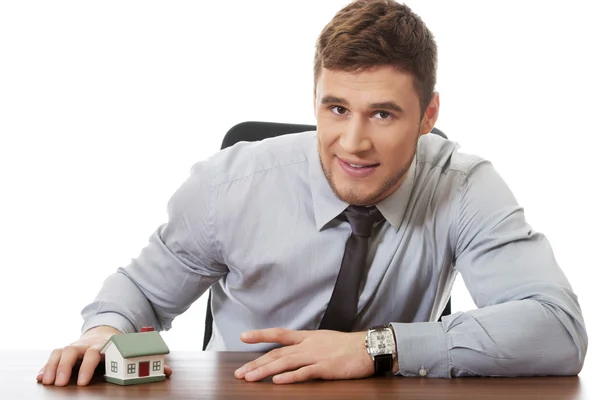 Businessman with house model by a desk. — Stock Photo, Image