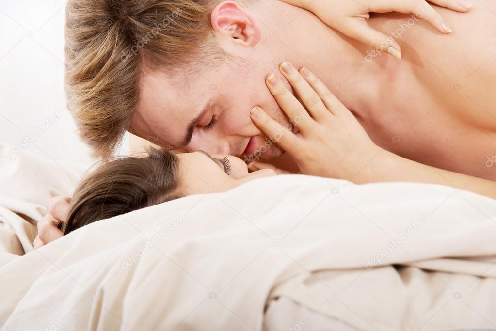 Young couple kissing on bed.